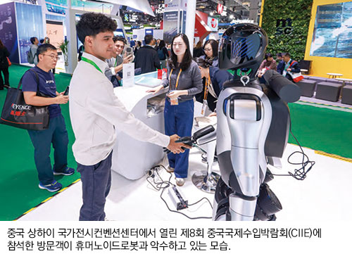중국 상하이 국가전시컨벤션센터에서 열린 제8회 중국국제수입박람회(CIIE)에 참석한 방문객이 휴머노이드 로봇과 악수하고 있는 모습.