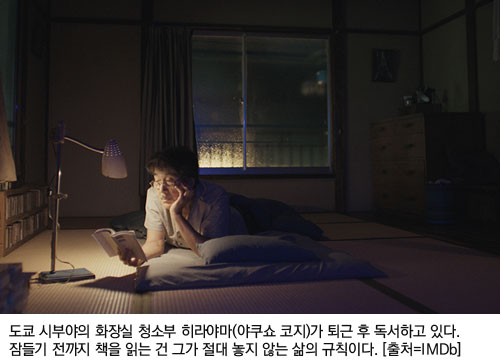 도쿄 시부야의 화장실 청소부 히라야마(야쿠쇼 코지)가 퇴근 후 독서하고 있다. 잠들기 전까지 책을 읽는 건 그가 절대 놓지 않는 삶의 규칙이다. [출처=IMDb]